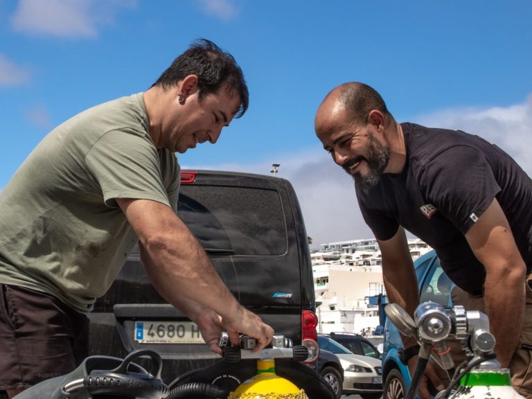 dos personas montando equipo de buceo, sonriendo, aprendiendo y disfrutando