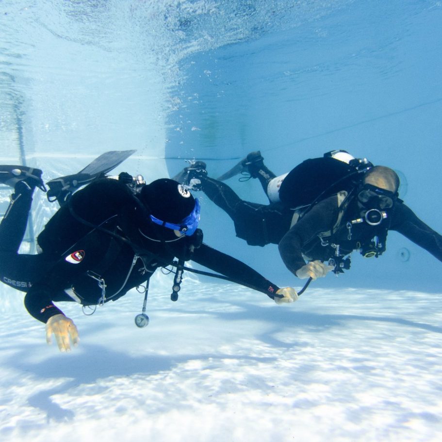 dos buzos practicando como compartir aire en una piscina